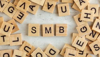 Top down view, pile of square wooden blocks with letters SMB (stands for Small to Medium Business ) on white board.